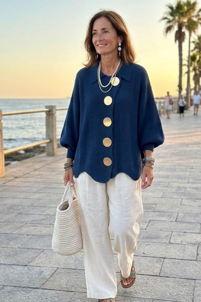 Mujer con chaqueta de punto azul marino y pantalón blanco